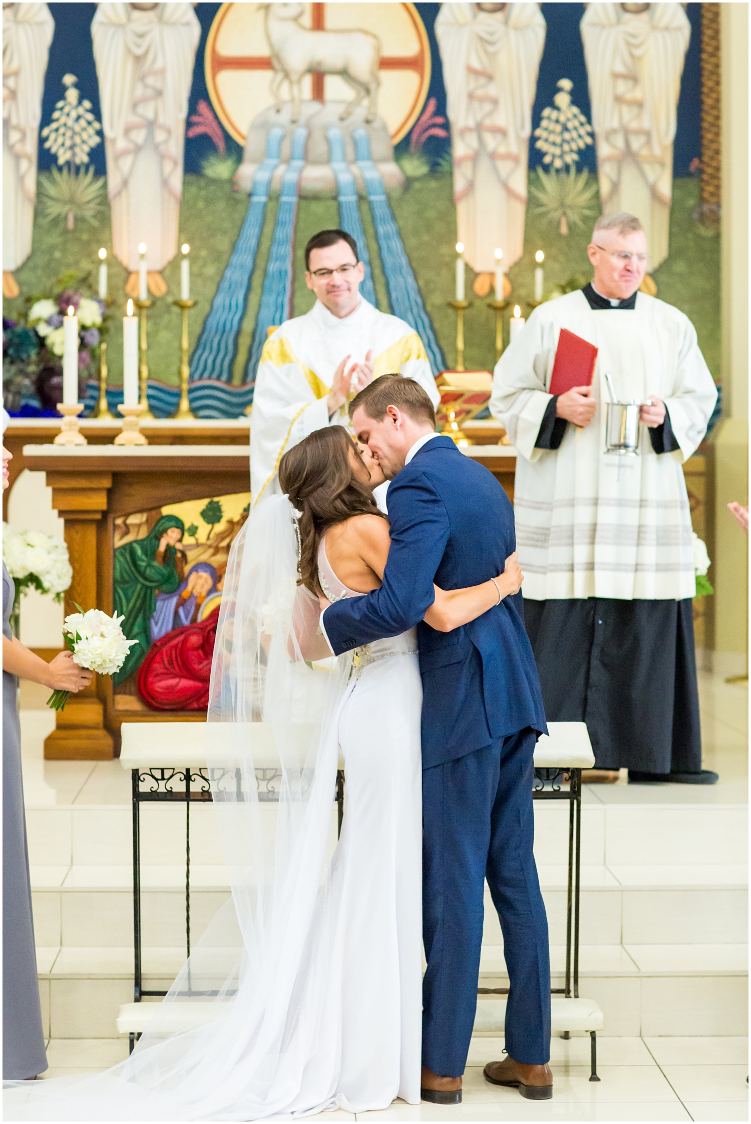 bride in demetrios bridal gown racerback with sheer beading with white hydrangeas bouquet with groom in navy blue suit with light blue tie in church first kiss on wedding day