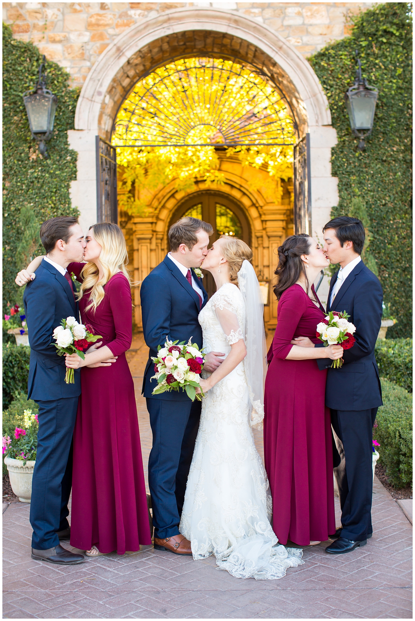 bride in sleeved lace dress with burgundy, white, and green wedding bouquet with bridesmaids in long sleeve burgundy dresses and groom in navy suit with burgundy tie with groomsmen wedding party portrait at Villa Siena