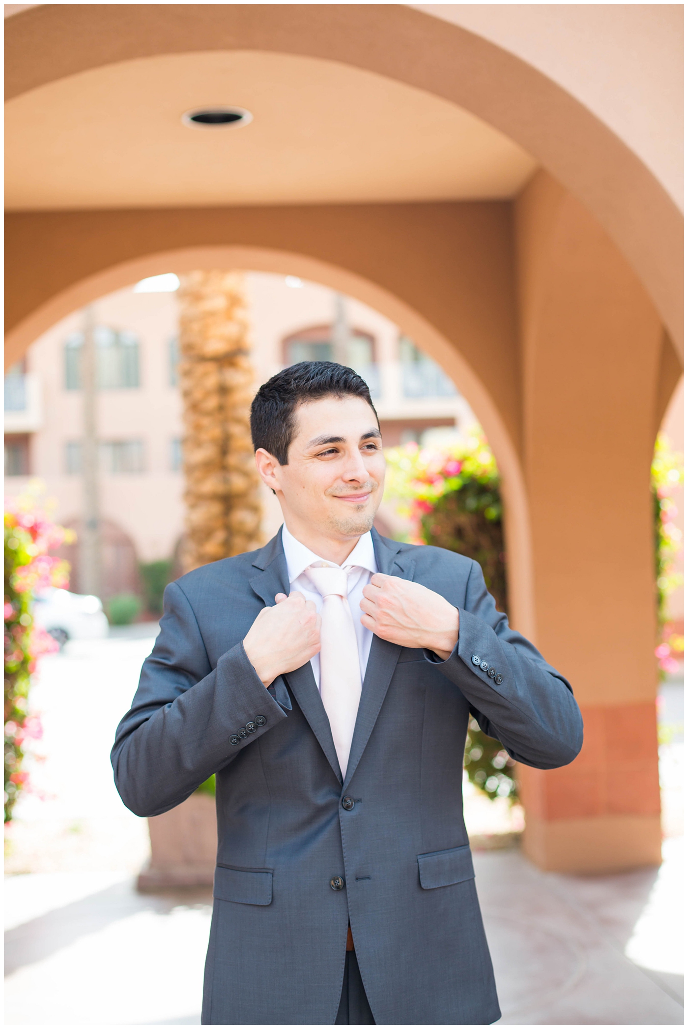 groom in gray suit with pink tie getting ready on wedding day