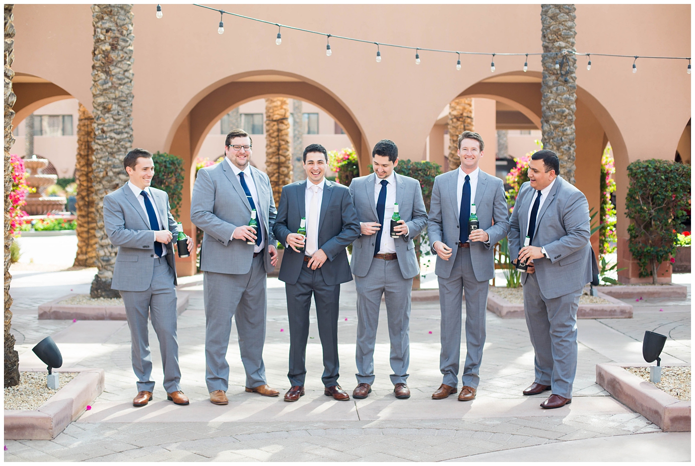 groom in gray suit with pink tie with groomsmen with navy ties getting ready on wedding day