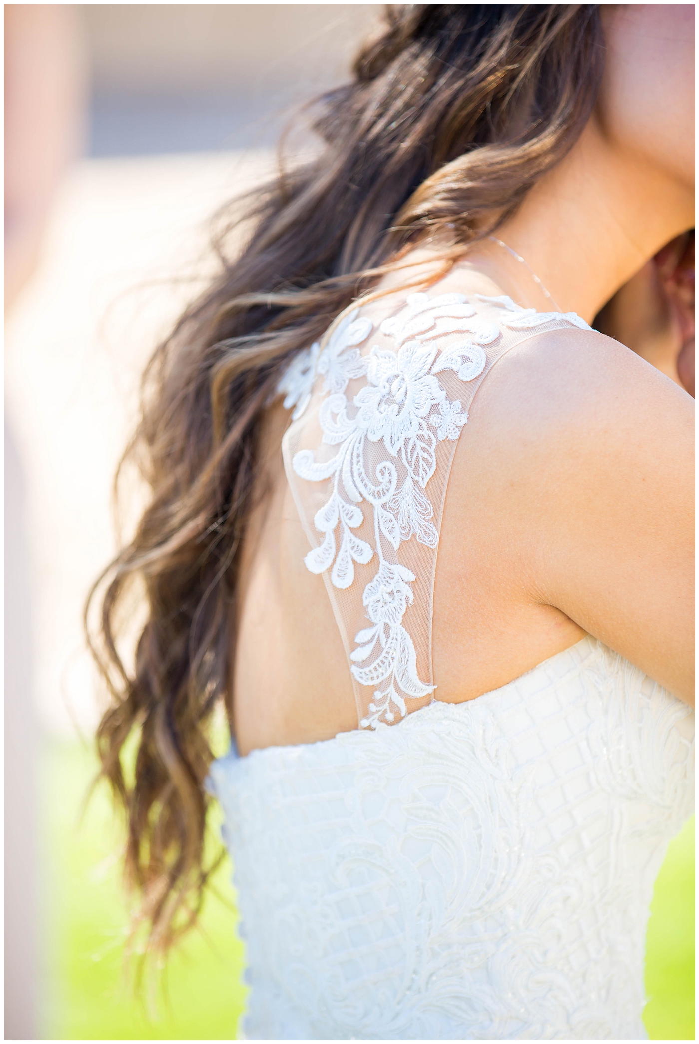 bride in lace cap sleeve wedding dress putting on earrings on wedding day