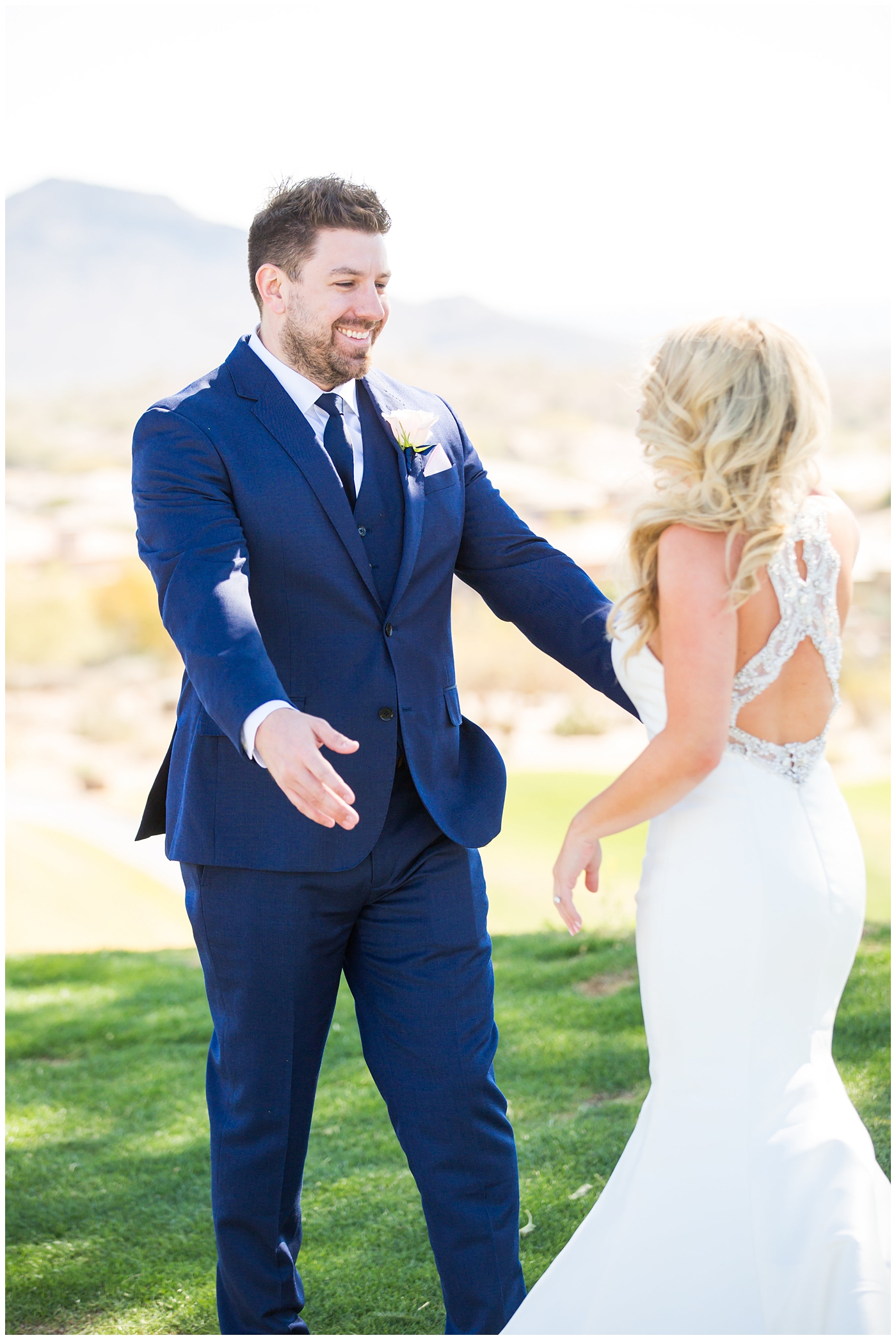 gorgeous bride with side swept hair in racerback pronovias dress with groom in navy suit and tie first look on wedding day
