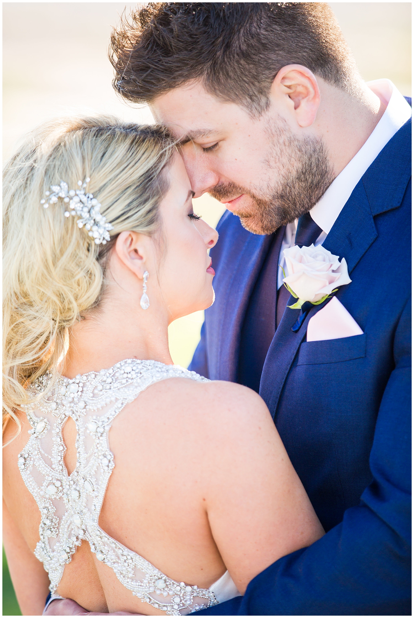 gorgeous bride with side swept hair in racerback pronovias dress and blush pink, white rose and eucalyptus greenery wedding bouquet with groom in navy suit and tie couple portrait on wedding day