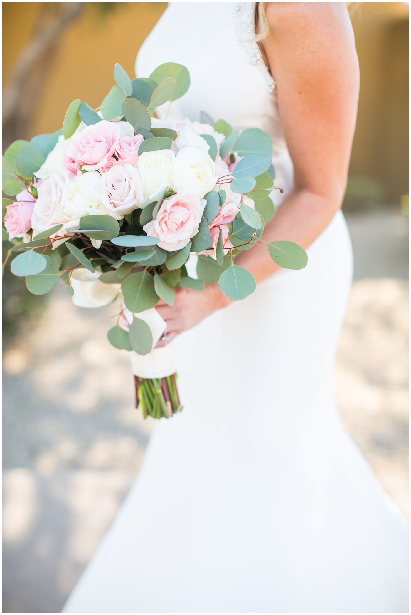 gorgeous bride with side swept hair in racerback pronovias wedding dress and blush pink, white rose and eucalyptus greenery wedding bouquet bridal portrait