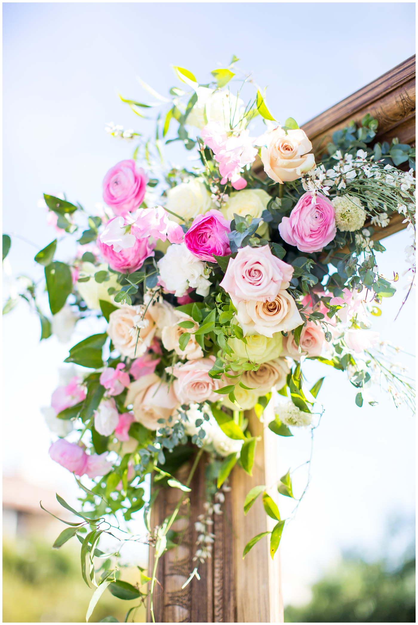 pink rose and greenery flower arrangment on picture frame arch for wedding ceremony