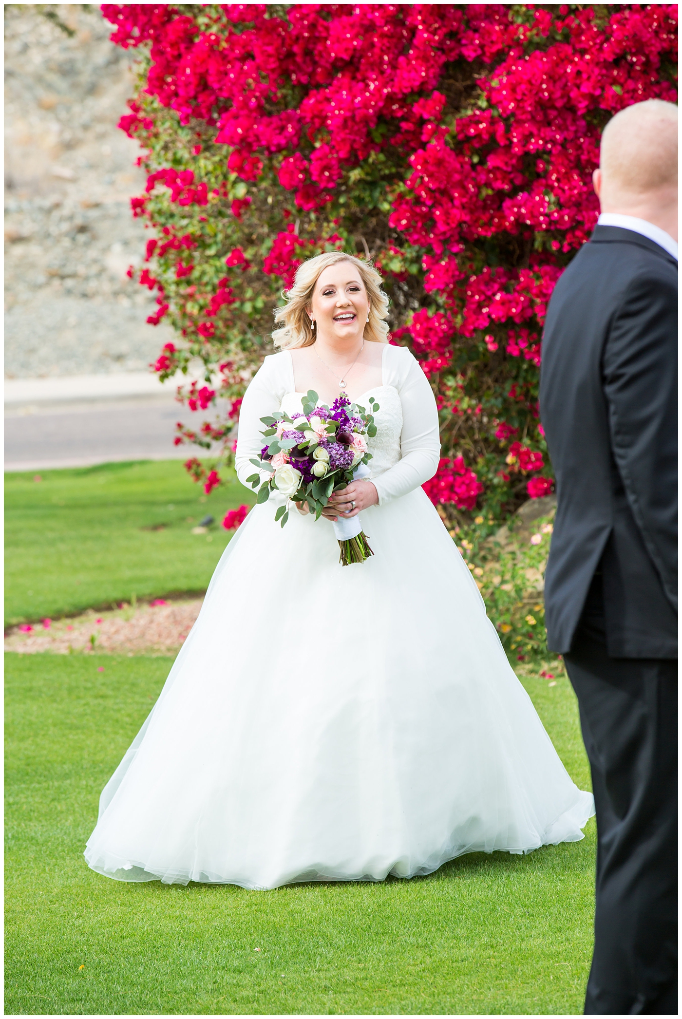 blonde bride in long sleeve wedding dress with purple and white flower bouquet and groom in black suit with purple calla lilly boutonniere first look on wedding day