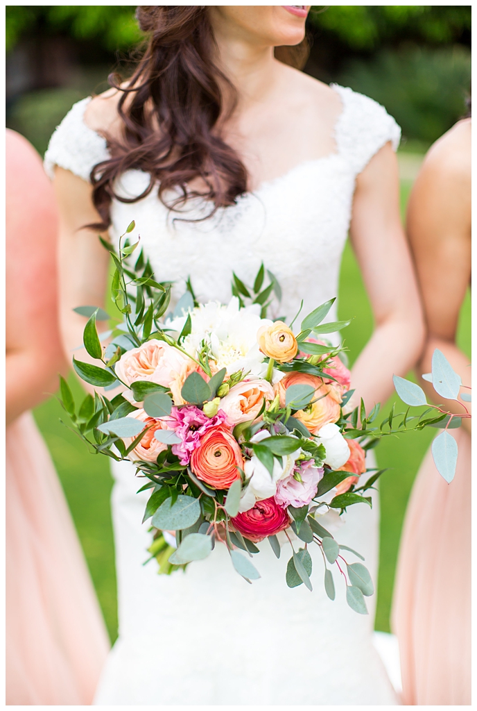 bride in matthew christopher wedding dress with cap sleeves with white, pink and orange ranunculus flowers and greenery bouquet wedding day portrait