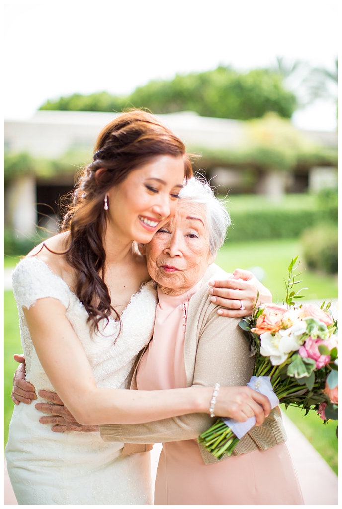 bride in matthew christopher wedding dress with cap sleeves with white, pink and orange ranunculus flowers and greenery bouquet wedding day portrait with grandmother