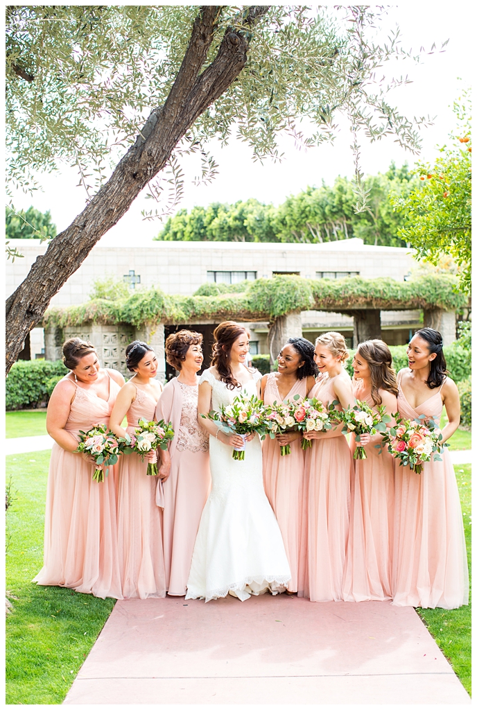 bride in matthew christopher wedding dress with cap sleeves with white, pink and orange ranunculus flowers and greenery bouquet with bridesmaids in blush wedding dresses portraits on wedding day at Arizona Biltmore