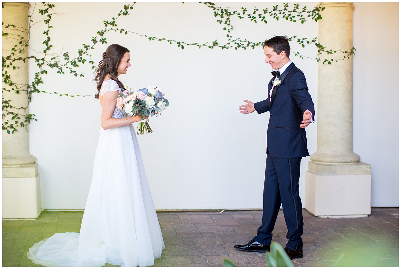 brunette bride in hayley paige wedding dress with cap sleeves with unique bouquet with succulents, white roses, peach peonies, and greenery with groom in dark blue and black tux with bowtie and white peony and succulent boutonniere wedding day first look