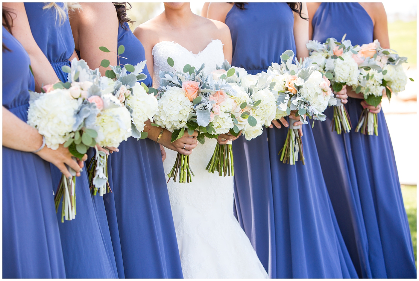 Bride in strapless maggie sorrento dress with soft white and pink roses bouquet with bridesmaids in long blue maxi dresses with bouquets bridal party wedding day pictures