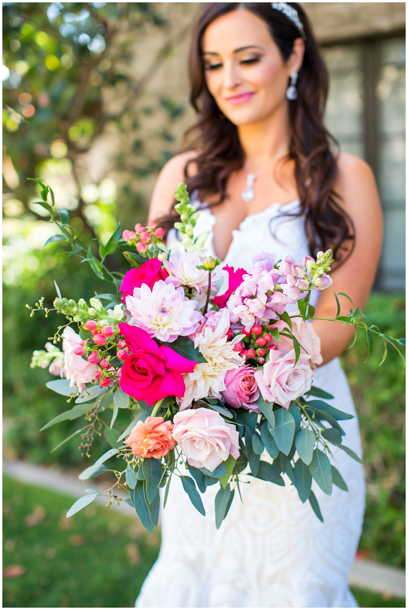 brunette long curly hair bride in wedding dress with thin straps with bright color roses, dahlia, snap dragons loose bouquet wedding day portrait