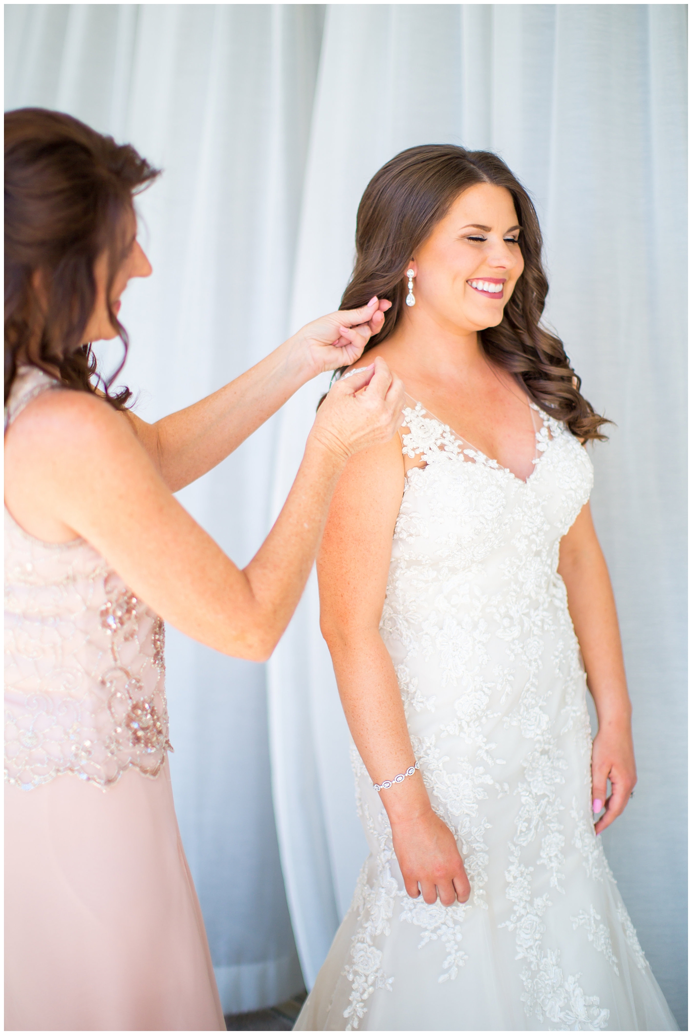 bride in wtoo watters wedding dress with lace straps getting ready on wedding day with mother