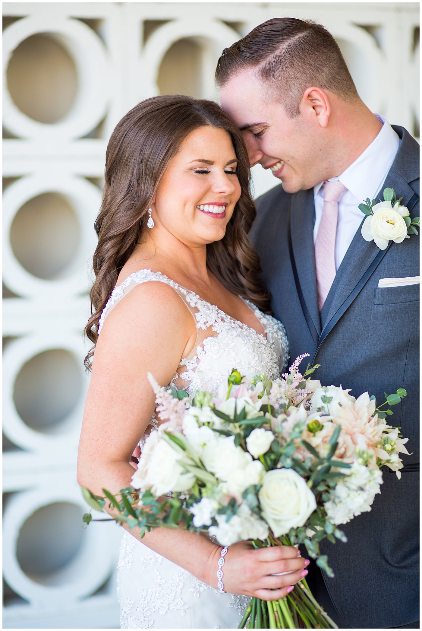 bride in wtoo watters wedding dress with lace straps with wildflower bridal bouquet with soft pink, blush, white, greenery flowers including roses, dahlias, snapdragons with groom in gray suit with pink tie and ranunculus boutonniere wedding day portrait