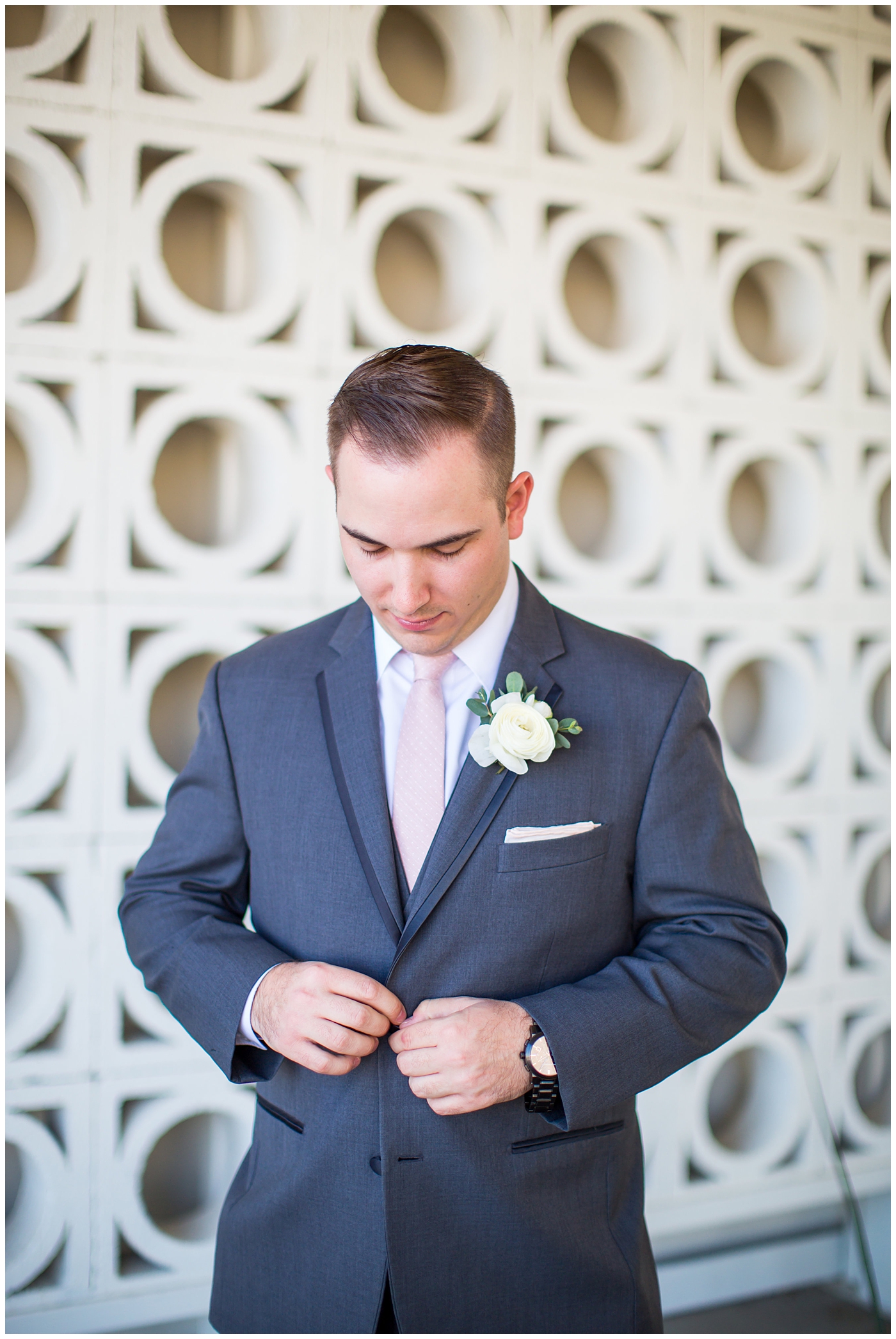 groom in gray suit with pink tie and ranunculus boutonniere portrait on wedding day